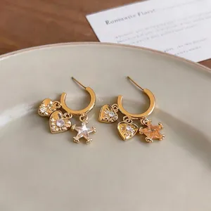 Minimalist C-shaped gold earrings with heart and star charms and sparkling zircon