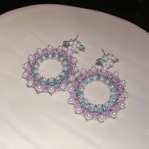 Detailed view of elegant silver floral earrings with pink zircons and pearls.