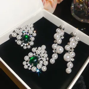 Close-up of elegant resin pearl earrings with green gemstones in a luxury jewelry box