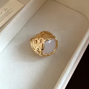 Gedetailleerde macro-opname van een vintage gouden ring met grote witte harssteen