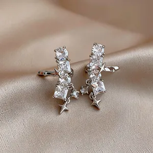 Detailed view of elegant silver star ear clips with clear zircons on beige satin