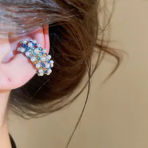 Close-up of a vintage C-shape ear cuff decorated with pearls and colorful rhinestones