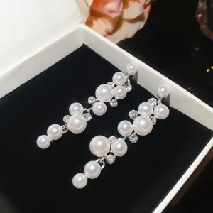Exquisite detail of elegant resin pearl and rhinestone dangle earrings inside a black jewelry box