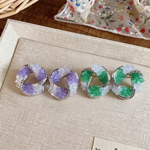 Geometric zircon glass shard earrings in purple and green styles on a beige tray