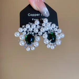 Detailed macro shot of luxury white resin pearl earrings with dark green stones