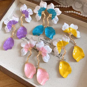 Detailed view of colorful enamel flower petal dangle earrings in a jewelry tray