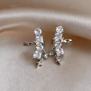Detailed macro view of silver zircon star ear clips on smooth champagne satin fabric