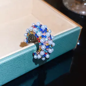 Detailed macro view of vintage C-shaped ear cuff with colorful rhinestones and pearls