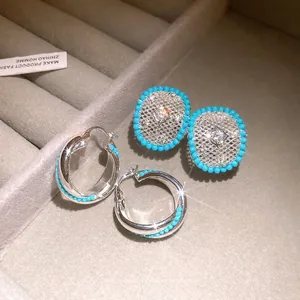 Elegant silver needle zircon earrings with blue beads and hollow mesh pattern.
