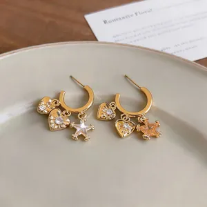 Macro view of gold C-shaped hoop earrings with zircon heart and star charms