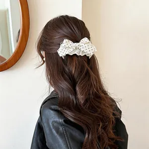 Elegante molletta per capelli con fiocco a pois bianchi su lunghi capelli castani
