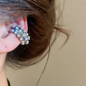 Close-up of a vintage C-shaped ear cuff with multi-colored rhinestones and pearls