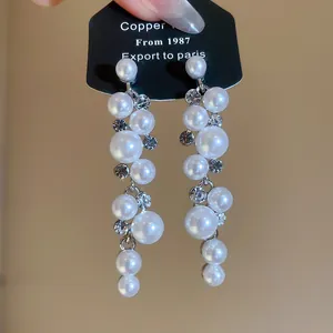 Close-up of elegant resin pearl dangling earrings with sparkling rhinestones.