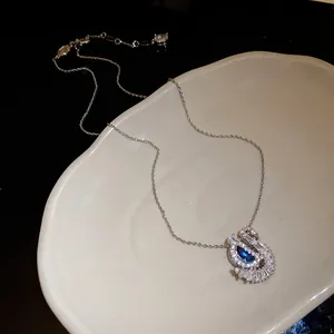 Vue détaillée d'un collier pendentif cygne orné d'une pierre de zircon bleue étincelante.