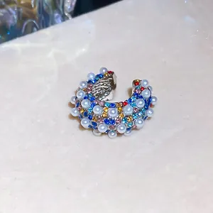 Close-up detail of C-shaped ear cuff with multi-color rhinestones and pearls