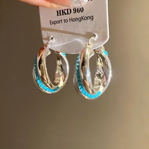 Elegant silver twisted hoop earrings featuring turquoise beads on white display card