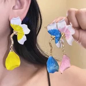 Detailed view of colorful enamel flower drop earrings in yellow, blue and pink