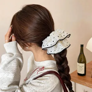 Dettaglio di un elegante elastico bianco a pois con bordo in pizzo su capelli intrecciati