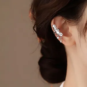 Close-up of a silver star ear cuff with sparkling zircons worn on a model's ear.
