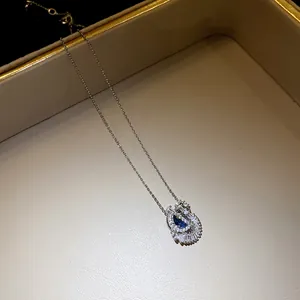 Vue détaillée du pendentif cygne élégant avec une pierre de zircon bleu étincelante.