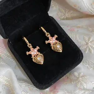 Detailed view of gold hoop earrings with pink star and zircon heart dangles