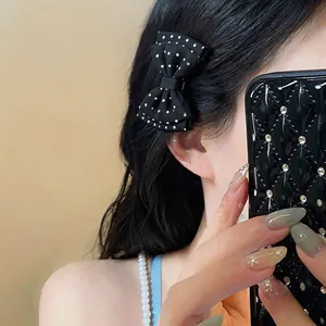 Primo piano di un fermaglio a fiocco nero a pois bianchi sui capelli scuri