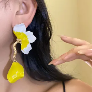 Detailed view of large yellow and white flower drop earrings on an Asian model's ear.