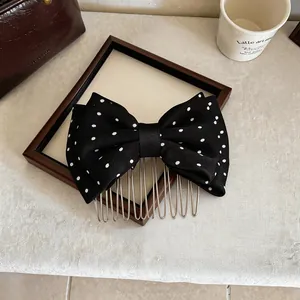 Dettaglio di un pettine per capelli in tessuto con fiocco nero a pois bianchi