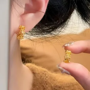 Detaillierte Makroansicht eleganter goldener hohlförmiger Spitzenblumenohrringe