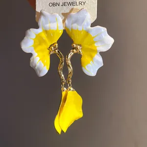 Close-up of yellow and white enamel flower earrings with gold-toned petals