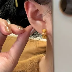 Detailaufnahme des filigranen, hohlen Spitzenblumendesigns dieser goldenen Ohrringe