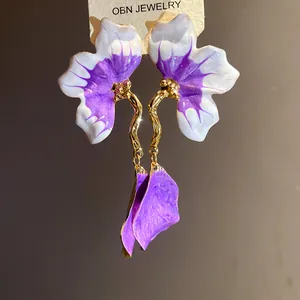 Detailed macro shot of elegant purple and white enamel flower petal drop earrings