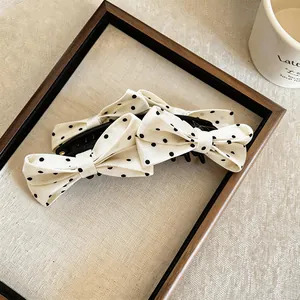 Primo piano di eleganti fermagli per capelli con fiocco in tessuto a pois in una cornice