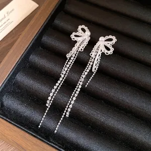 Elegant silver bow tassel earrings with pearls and zircons on black velvet box