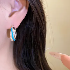 Detailed view of minimalist silver hoop earrings featuring blue beaded accent on ear