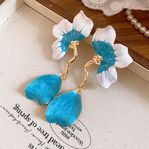 Macro detail view of elegant blue and white enamel flower earrings with golden stems