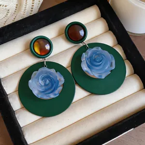 Detailed macro shot of vintage French style dark green rose earrings in a jewelry box