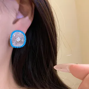 Macro view of round hollow grid stud earrings with turquoise beads and zircon
