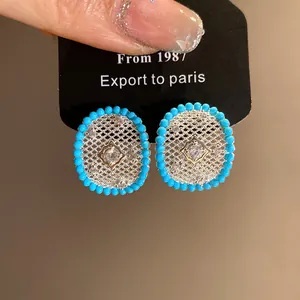 Detail showing silver-tone hollow mesh stud earrings with turquoise-colored beads