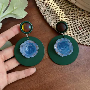 Detailed view of vintage French green circular earrings with blue resin rose center.