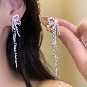 Detailed macro view of elegant silver bow earrings with zircon tassels and a central pearl