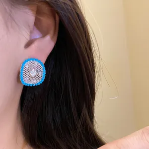 Detailed macro view of a silver needle hollow mesh stud earring with turquoise beads