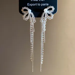 Silver lace bow earrings with pearls and crystal tassels, elegant jewelry detail shot.