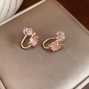 Detailed macro view of rose gold cat paw clip-on earrings featuring pink cat eye stone