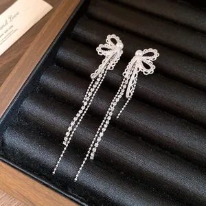 Detailed shot of silver bow earrings with lace design and pearl accents