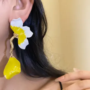 Close-up view of vibrant yellow and white enamel flower earrings worn by an Asian model
