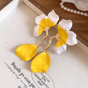 Detailed macro view of yellow and white enamel flower earrings with gold finish accents