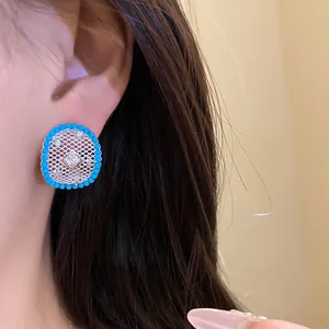 Close-up view of silver mesh stud earring with turquoise bead border on model's ear