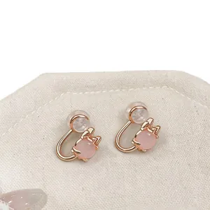 Exquisite pink cat's eye stone ear clips with rose gold cat paw design on canvas.