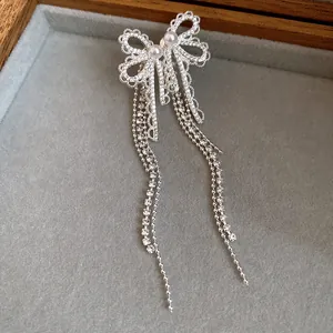 Elegant silver bow earrings with pearls and long flowing tassels detail view